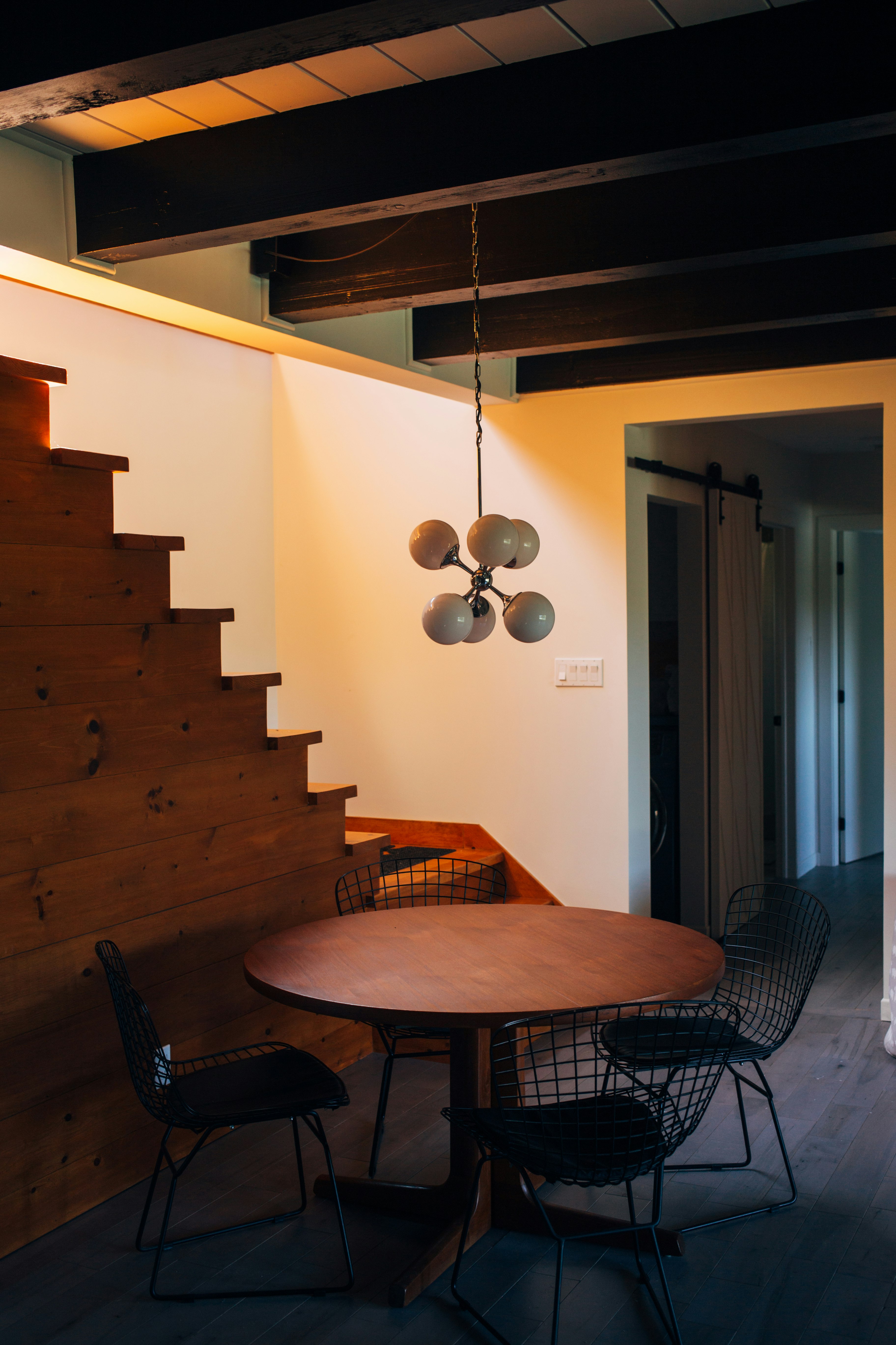 round brown wooden table and chairs under white pendant lamp